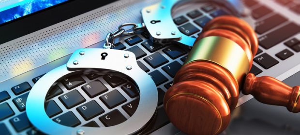 Handcuffs and judge mallet on laptop keyboard